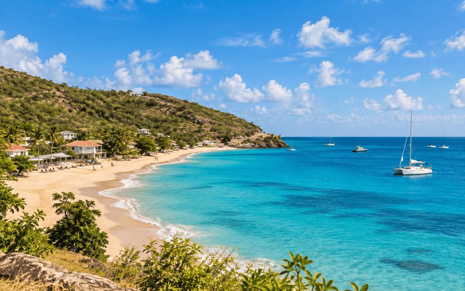 Elevated view of a turquoise bay, sandy beach and terracotta-roof buildings in Antigua