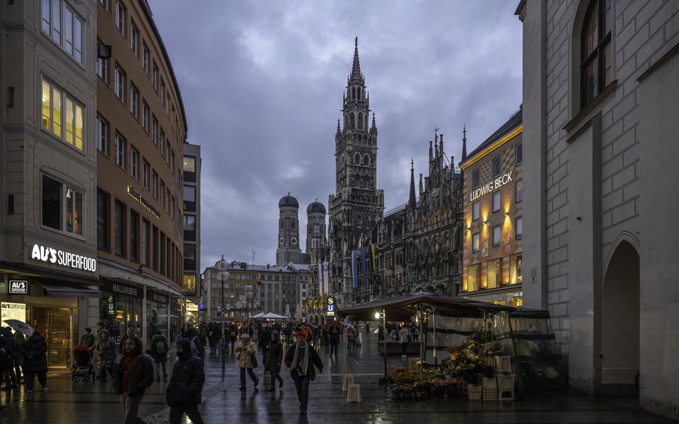 Marienplatz in Munich at twilight with the New Town Hall tower, Frauenkirche domes and pedestrians in winter coats