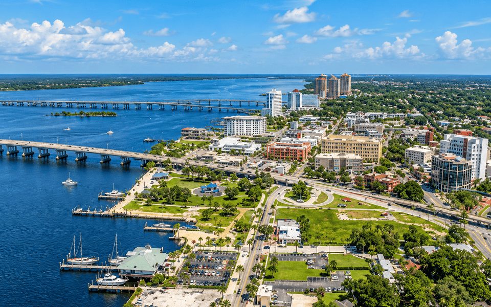 Sunny Tampa-area waterfront with bridges, marina docks and palm-lined park along the bay
