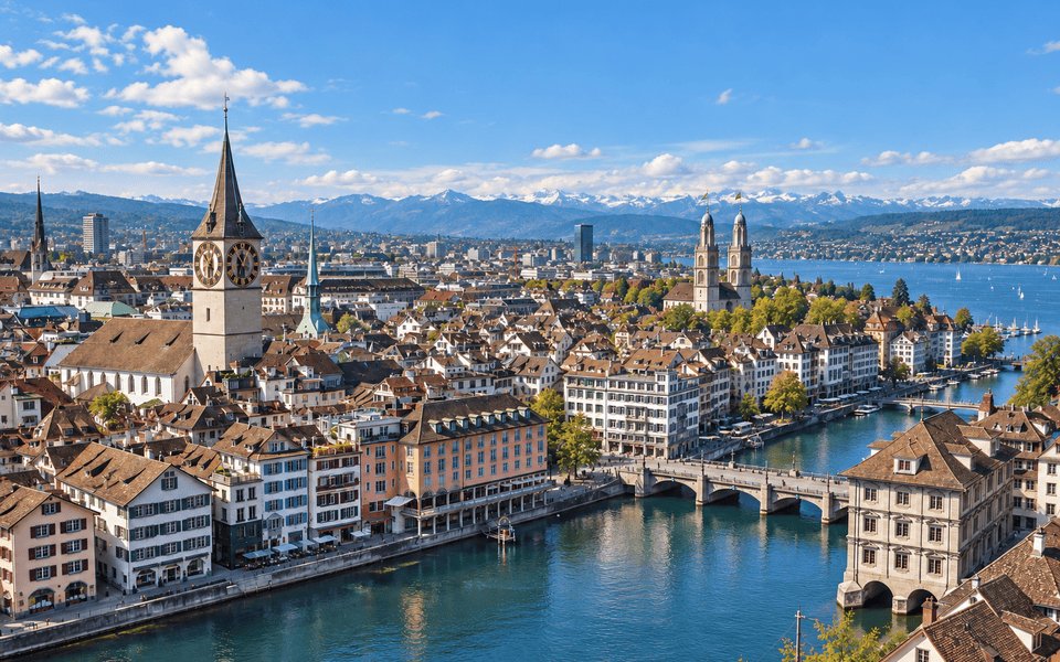 Aerial view of Zurich along the Limmat with St. Peter clock tower, Grossmünster and the Alps beyond