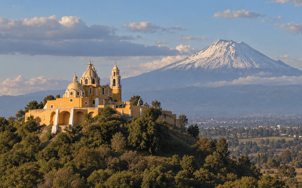 Yellow church of Nuestra Señora de los Remedios at Cholula with snow-capped Popocatépetl for international December flight deals from New York