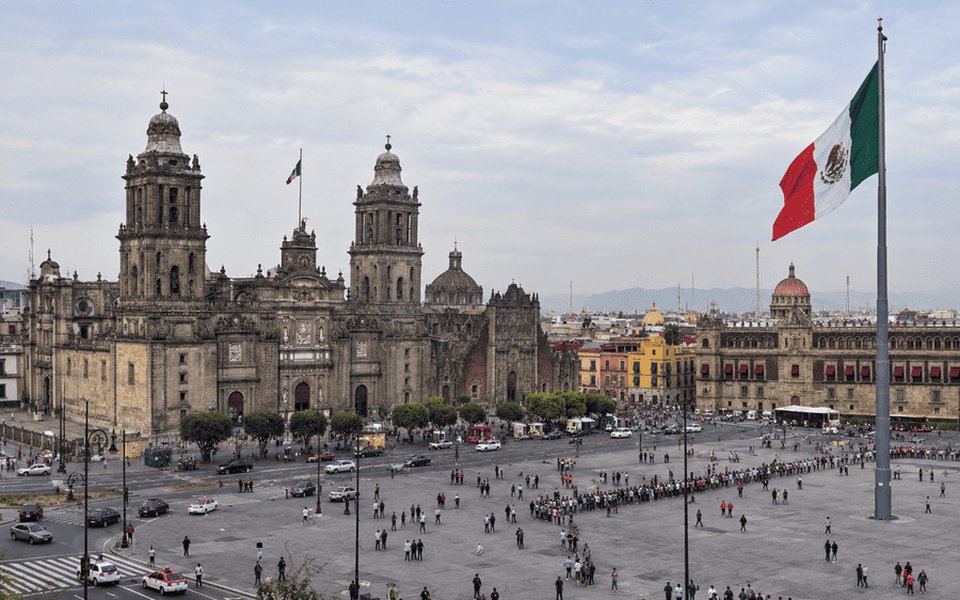 Mexico City Zócalo with the Metropolitan Cathedral, National Palace and a large Mexican flag for November flight deals from Vancouver